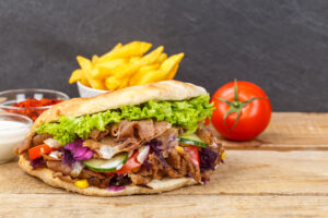 Döner Kebab Doner Kebap fast food meal in flatbread with fries on a wooden board and copyspace copy space
