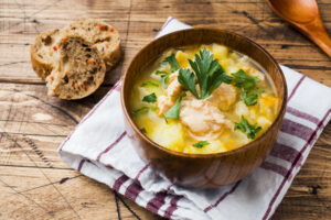 Fish soup in a wooden bowl with fresh herbs.