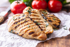 Grilled chicken breast on butcher board close up