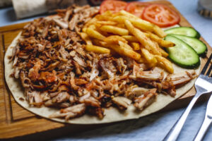 side view iskander doner on pita with french fries fresh cucumber and tomato