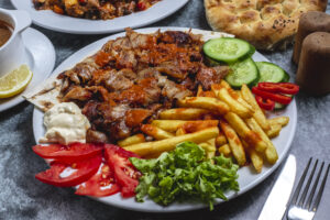 side-view-doner-plate-with-french-fries-tomato-fresh-cucumber-yogurt-bread-table