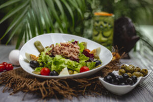 side view of tuna salad with cherry tomatoes and olives in a white plate